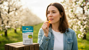 Woman holding a Breathe Better plant-powered lozenge outdoors in a spring orchard.