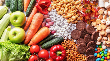 Fresh vegetables and fruits with candy, popcorn, cookies, gummy bears, and pretzels arranged side by side