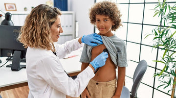 Female doctor using a stethoscope to examine a young boy's heart in a medical office.