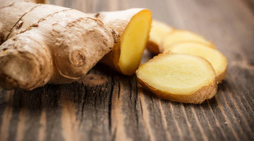 Fresh whole ginger root and sliced ginger pieces on a rustic wooden surface