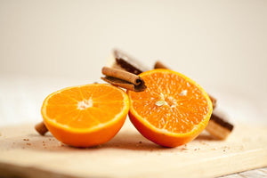 Two halves of a fresh orange with cinnamon sticks on a wooden surface