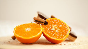 Two halves of a fresh orange with cinnamon sticks on a wooden surface