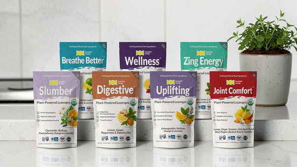 Assorted Essential Candy health supplement packages on a white surface with a plant in the background