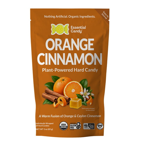 A 3 oz stand-up pouch of Essential Candy Orange Cinnamon plant-powered hard candy, featuring a warm orange-brown background with illustrations of oranges, cinnamon sticks, and a candy cube.