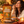 Load image into Gallery viewer, A woman in a cozy indoor setting enjoys a piece of orange cinnamon hard candy while holding a bag of Essential Candy Orange Cinnamon plant-powered hard candy. The scene is decorated with fresh oranges, cinnamon sticks, a small bowl of candy, and a warm candle on a wooden table.
