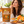Load image into Gallery viewer, A woman in a cream knit sweater is shown eating an orange cinnamon hard candy while a stand-up pouch of Essential Candy Orange Cinnamon candy sits beside her on a kitchen counter with oranges, cinnamon sticks, and a bowl of candy.

